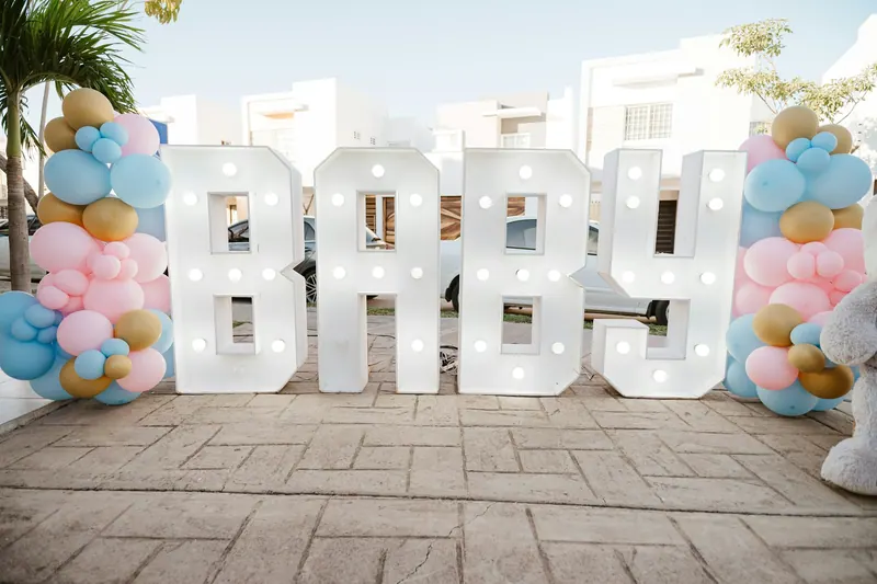 Light-up BABY letters flanked by pastel pink, blue and gold balloons