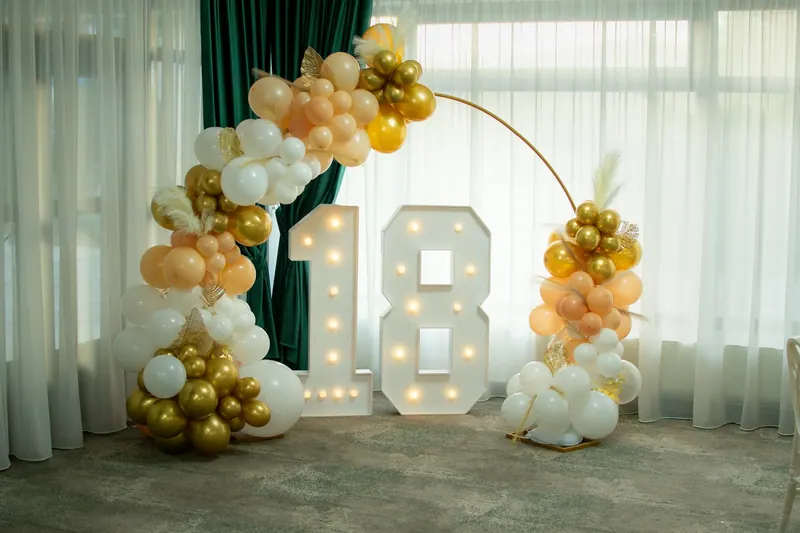 Light-up 18 marquee numbers framed by a gold, peach and white balloon arch