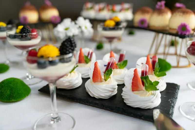 Mini pavlovas with strawberries and panna cotta glasses on a dessert table