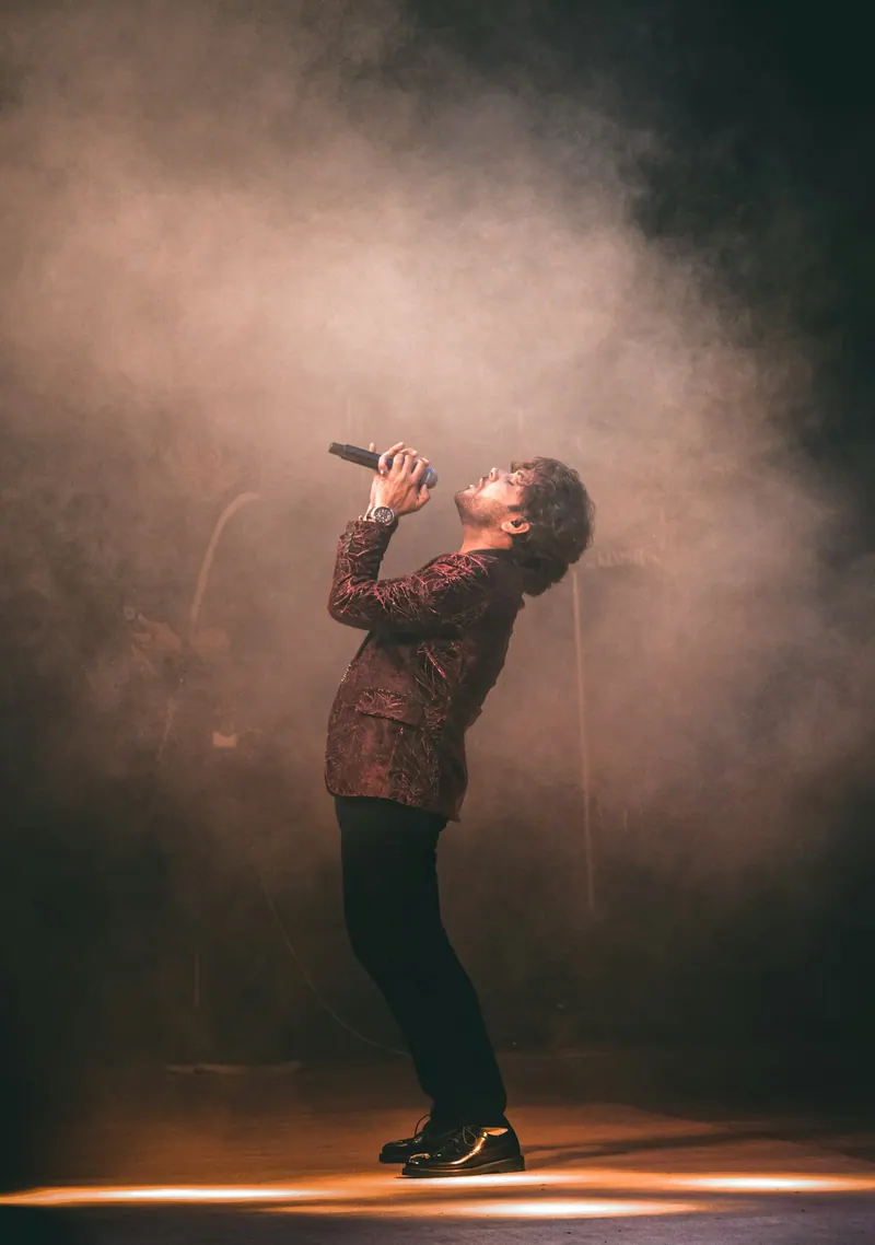 Singer performing in a haze-filled spotlight on stage