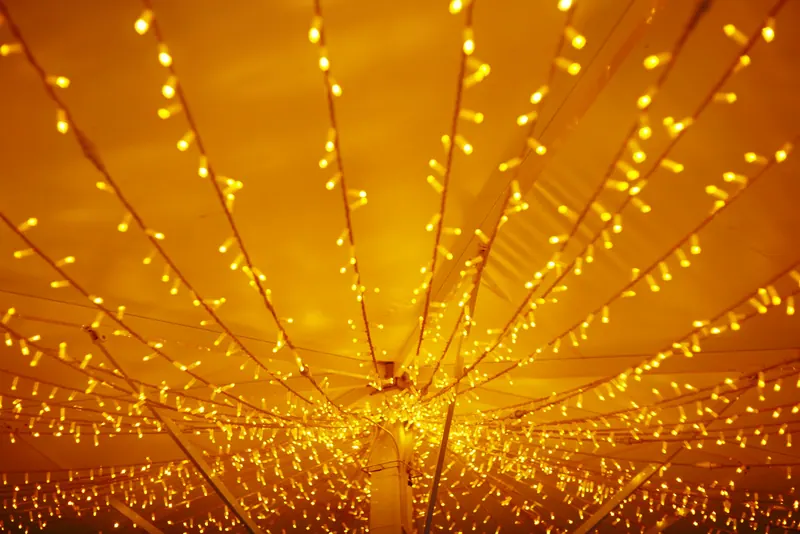 Hundreds of warm fairy lights radiating across a glowing tent ceiling