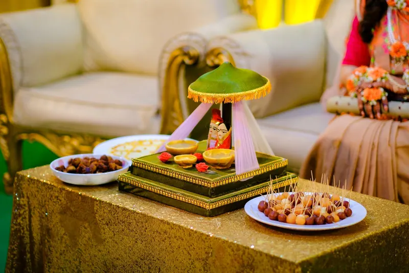 Ring ceremony table with a decorated ring platter, sweets and dry fruits beside a gold sofa