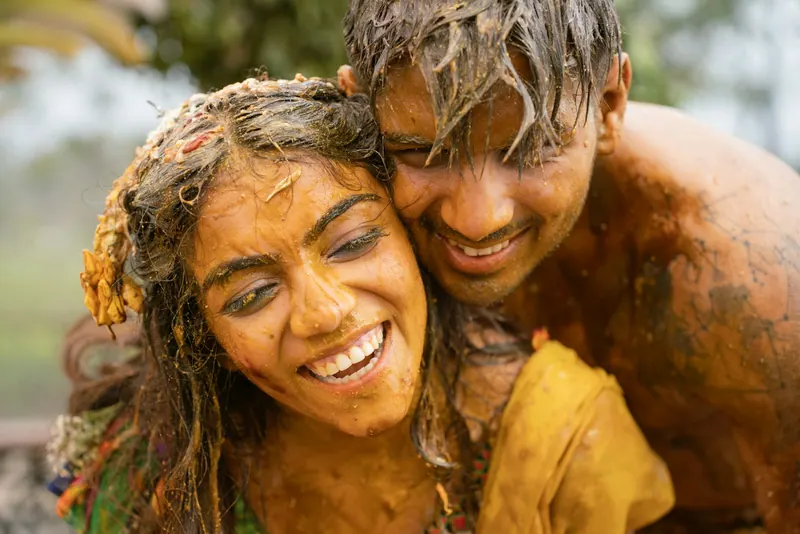 Couple covered in turmeric paste laughing and embracing during the haldi