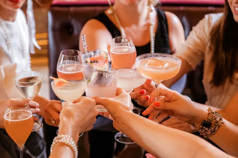 Friends clinking colourful cocktails at a private party