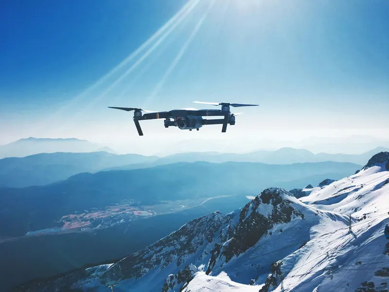 Camera drone flying above snowy mountain ridges