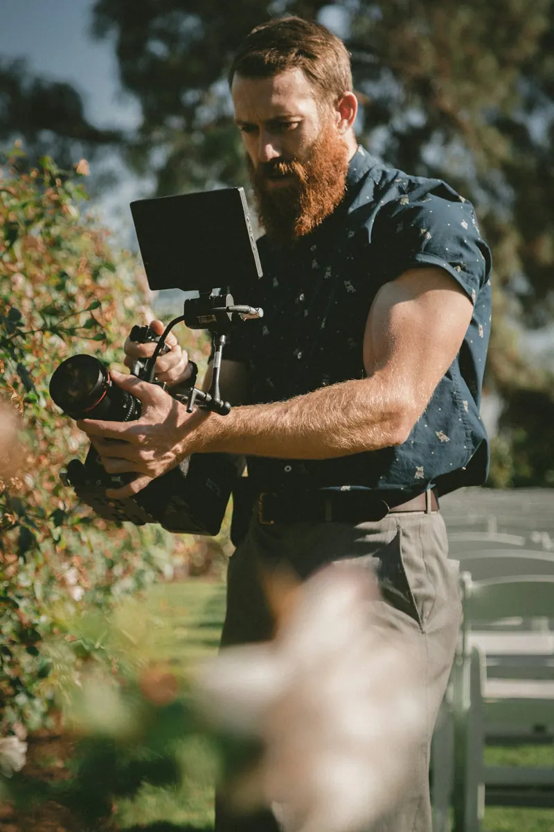 Videographer filming outdoors with a camera rig and monitor