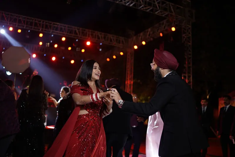 Couple dancing under stage lights and a lighting truss at an evening sangeet