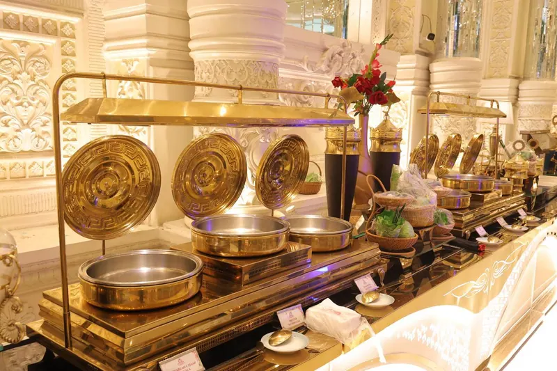 Brass chafing dishes with engraved lids lined up along a buffet