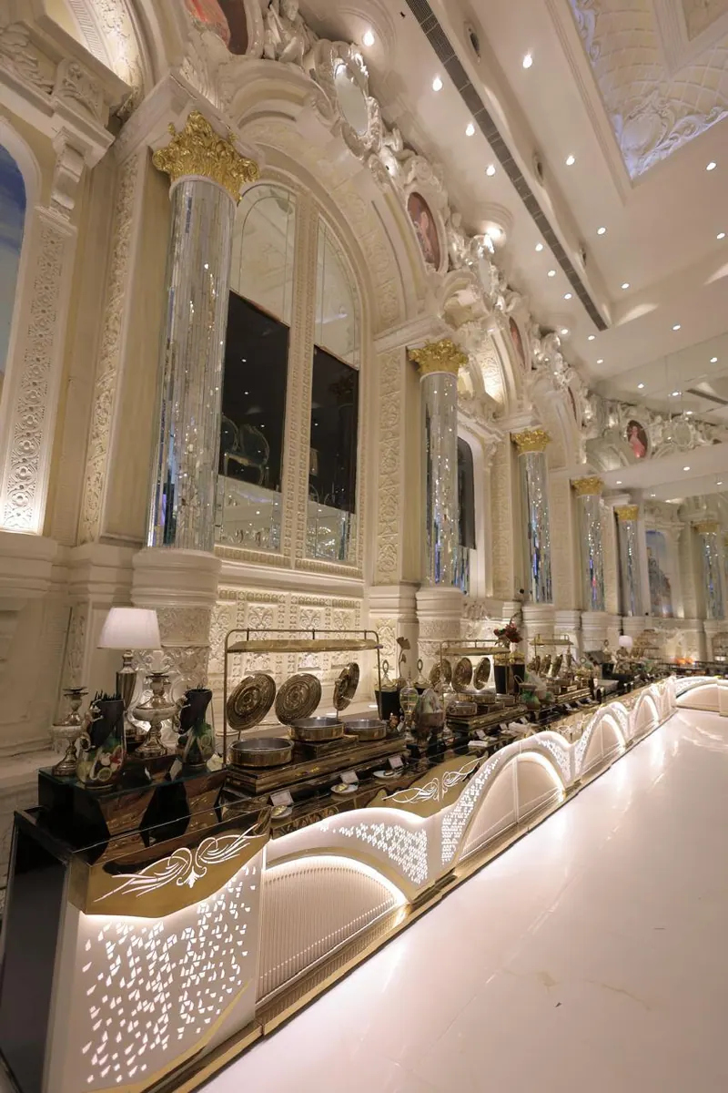 Lit buffet counter running along an ornate carved gallery wall