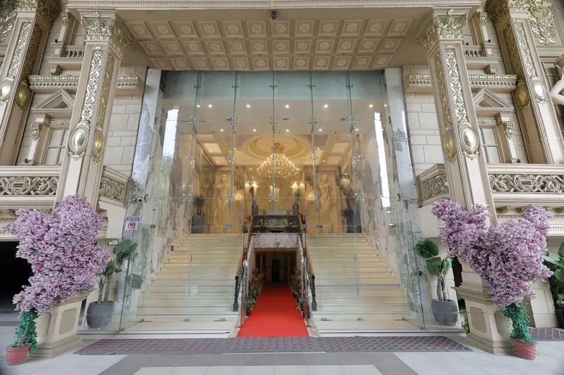 Grand entrance with a red-carpeted staircase between lilac blossom trees