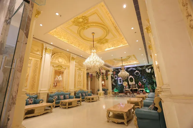 Gold-ceilinged lounge hall with teal sofas and a greenery photo corner