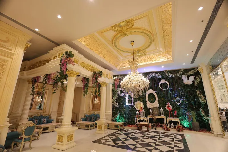 Pillared lounge with a greenery photo wall, vintage frames and a chandelier